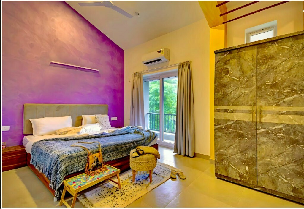 Secondary bedroom with purple accent wall and marble-finish wardrobe in Sector 57 Gurgaon home