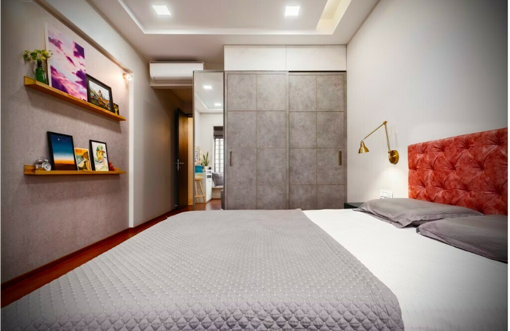 Master bedroom with tufted headboard and full-height grey wardrobe in Gurgaon 3BHK interior by Arqvexa