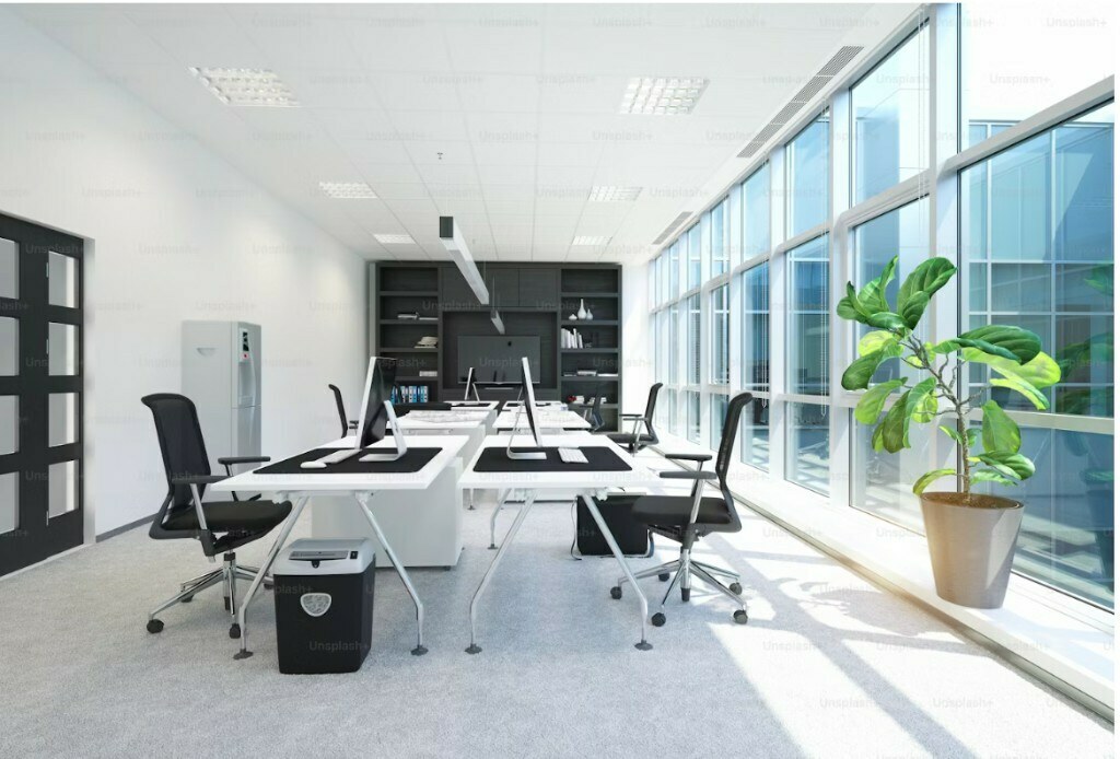 Minimal white open office with ergonomic black chairs and built-in shelving in Noida